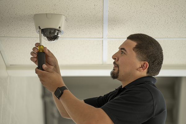 A man installs a video security camera in the ceiling.